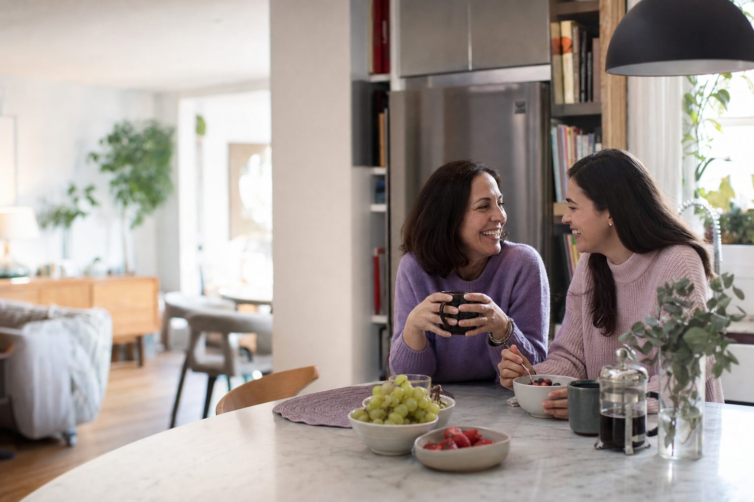 Two colleagues talking warmly at a table in a bright home